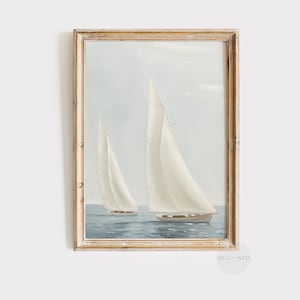 May include: A framed painting of two sailboats on a calm blue sea with a light blue sky. The sailboats are white with brown hulls. The frame is a light wood color.
