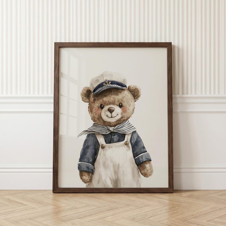 May include: A framed watercolor illustration of a brown teddy bear dressed as a sailor. The bear wears a white and navy blue sailor hat with a gold anchor emblem, a navy blue long-sleeved shirt, a striped neckerchief, and white overalls.