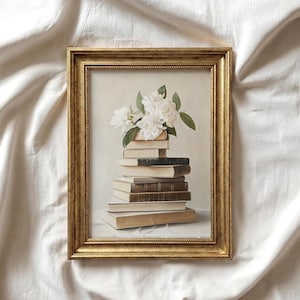May include: A rectangular wall art print in a distressed gold frame featuring a stack of seven books of varying shades of beige, brown, and dark green. Resting on the top book is a cluster of white gardenia flowers with green leaves.