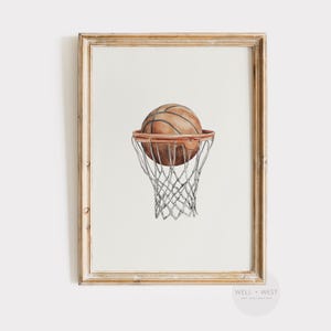 Può includere: Stampa ad acquerello di un pallone da basket che entra in un canestro. Il pallone è marrone con linee nere, e il canestro è marrone con una rete bianca. L'opera è in una cornice dorata.