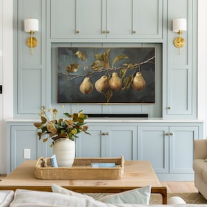 Puede incluir: Un televisor rectangular montado en la pared que muestra un bodeg&oacute;n de cuatro peras en una rama con hojas verdes sobre un fondo oscuro, colocado sobre un mueble azul claro con dos apliques de pared de lat&oacute;n y una encimera blanca.