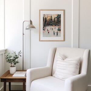 May include: A framed art print depicting an outdoor ice skating scene with people on a rink surrounded by trees and string lights. The illustration features a soft color palette with figures in various winter clothing skating on the ice.