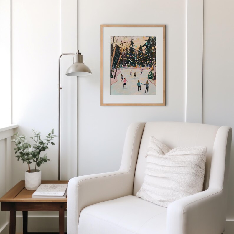 May include: A framed art print depicting an outdoor ice skating scene with people on a rink surrounded by trees and string lights. The illustration features a soft color palette with figures in various winter clothing skating on the ice.