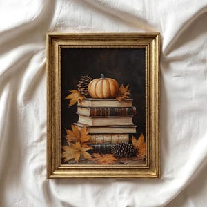 Puede incluir: Pintura enmarcada que presenta una pila de libros antiguos, coronada por una pequeña calabaza, piñas y hojas de otoño. La obra de arte tiene un fondo oscuro y un marco dorado, evocando un tema de cosecha otoñal.