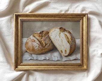 Peut inclure: Peinture encadrée de deux pains, dont l'un est coupé pour révéler l'intérieur. Le pain est brun doré avec une croûte texturée, posé sur un tissu blanc. Le cadre est doré et le fond est de ton neutre.