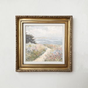 May include: A framed landscape painting depicting a coastal scene. The artwork features a path leading to the ocean, surrounded by wildflowers in shades of pink, red, and yellow. The frame is ornate, gold-colored, and adds a classic touch to the artwork.