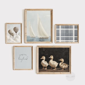 May include: A gallery wall with five framed prints. The prints feature a sailboat on the sea, a plaid pattern, hot air balloons, ducklings, and the text "Long Live Boyhood".