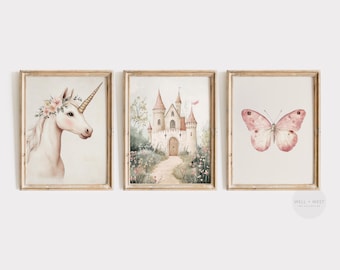May include: Set of three framed watercolor prints. The prints feature a unicorn with a floral crown, a castle with a path leading to it, and a pink butterfly. The frames are a light wood color.