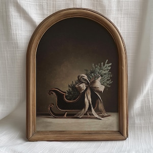 May include: A framed painting of a Christmas scene. A black sleigh is filled with a small evergreen tree and a large striped bow. The painting is set in a wooden frame with an arched top.
