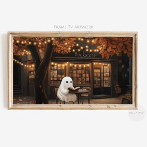 Puede incluir: Obra de arte enmarcada que representa una acogedora escena de librería. Un fantasma amigable está sentado en una mesa leyendo un libro, con una librería al fondo. La escena está iluminada por cálidas luces de cadena y follaje otoñal. El texto "Bookstore" es visible.