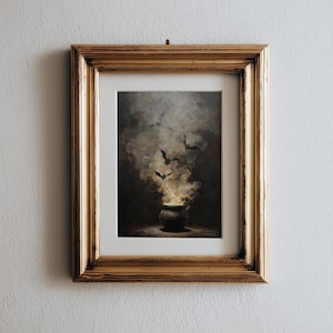 May include: A framed print showing a cauldron with smoke and bats. The artwork has a dark, atmospheric colour scheme and a gold frame. The cauldron is at the bottom, with smoke rising, and bats flying above.