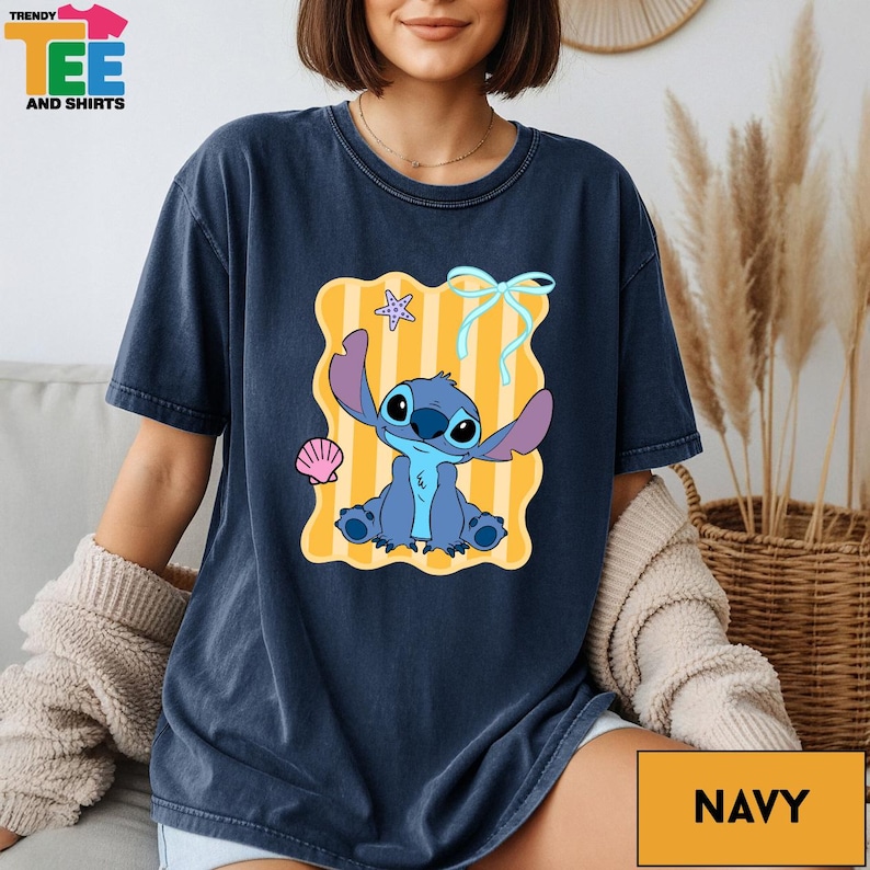 A woman wearing a navy blue t-shirt with a cartoon character printed on it, sitting on a couch.