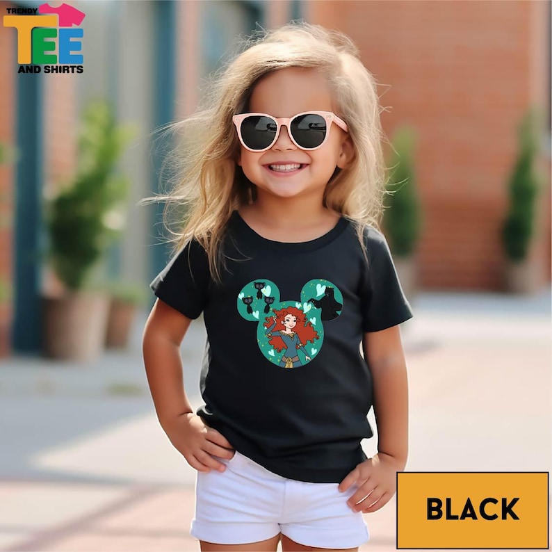 A young girl wearing a black t-shirt with a Disney character design and sunglasses, smiling at the camera.