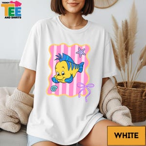 A woman wearing a white t-shirt with a cartoon fish design and a pink and white striped background.