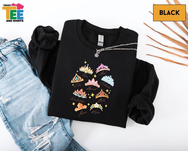 a black sweatshirt with a colorful crown design, a pair of blue jeans, and a black shirt with a chain.