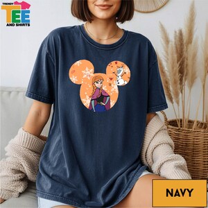 A woman wearing a navy blue t-shirt with a graphic of a character from the Disney movie Frozen.