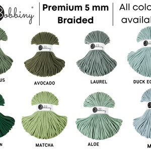 Może przedstawiać: Kolekcja 5 mm plecionej sznurka bawełnianego w r&oacute;żnych odcieniach zieleni i błękitu. Kolory obejmują Eucalyptus Green, Avocado, Laurel, Duck Egg Blue, Pine Green, Matcha, Aloe i Misty. Sznurek jest oznaczony "Bobbiny Premium 5 mm Braided" i "Wszystkie kolory dostępne".