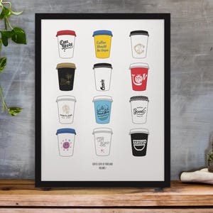 May include: A framed print featuring twelve illustrated coffee cups with various lid colors and text. The cups are arranged in a grid, each with a unique design and message. The print is titled "Coffee Cups of Portland Volume 1."