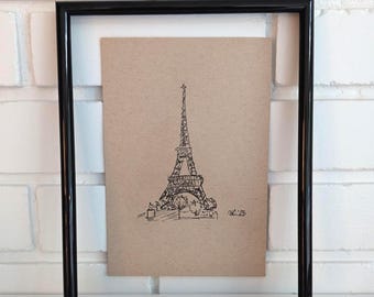 May include: A framed pen and ink drawing of the Eiffel Tower. The artwork is on tan paper and set within a black frame. The drawing depicts the iconic Parisian landmark with detailed lines and shading, capturing its architectural features.