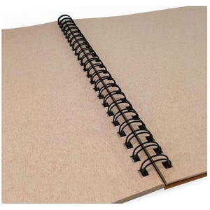 May include: An open notebook with blank, light brown pages. The pages are bound together with a black spiral binding. The notebook is ideal for sketching, journaling, or note-taking.
