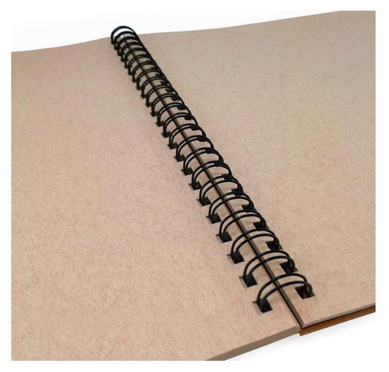 May include: An open notebook with blank, light brown pages. The pages are bound together with a black spiral binding. The notebook is ideal for sketching, journaling, or note-taking.