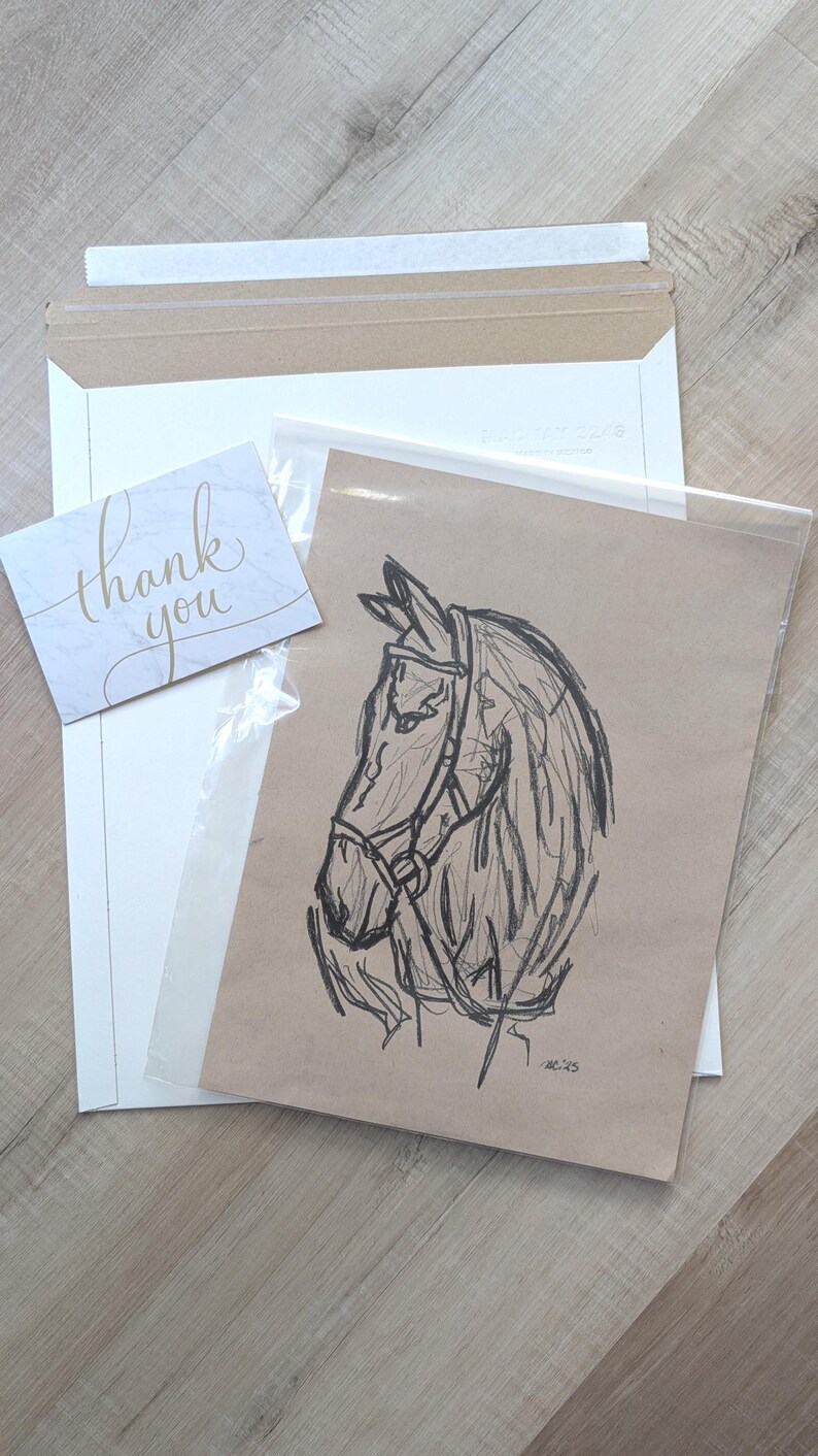 May include: A sketch of a horse's head in profile, rendered in black pencil on brown paper. The horse wears a bridle. A small card with "thank you" in gold script is included, along with a white envelope and a clear plastic sleeve.