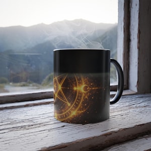 May include: Black ceramic mug with a gold pentagram and crescent moon design. The mug is filled with a hot beverage, with steam rising. The mug is set on a rustic, white-painted wooden windowsill.