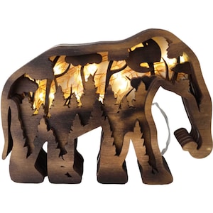 May include: A wooden elephant silhouette with a forest scene cut out inside. The elephant is lit from within with warm white LED lights.