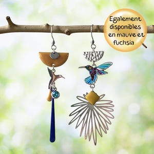 May include: Two decorative dangle earrings. One has a brown semi-circle, a hummingbird charm, and a blue teardrop. The other features a silver half-circle, a hummingbird, and a silver flower. The text says "Also available in purple and fuchsia."