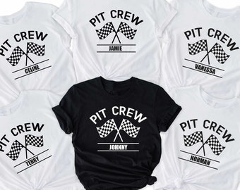 Puede incluir: Cinco camisetas blancas con texto negro y un diseño de bandera a cuadros. El texto dice "PIT CREW" con un nombre debajo. Una camiseta negra con texto blanco y un diseño de bandera a cuadros. El texto dice "PIT CREW" con el nombre "JOHNNY" debajo.