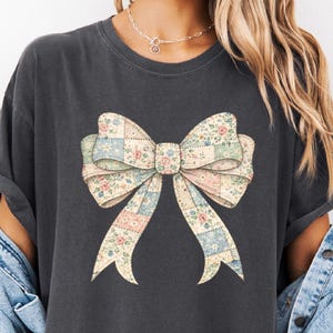 A woman wearing a black t-shirt with a large bow design on it.