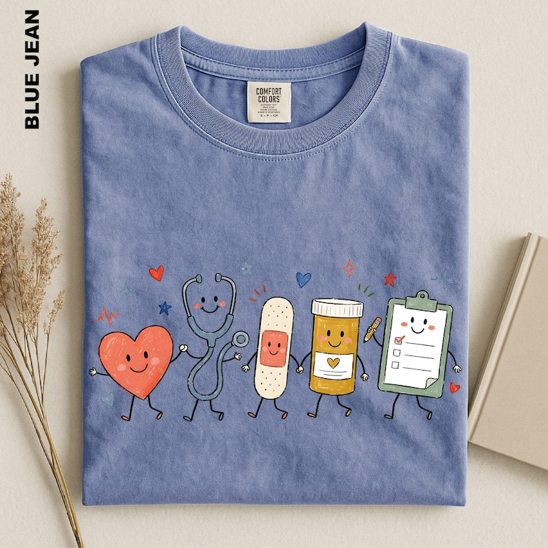 A blue t-shirt with a colorful illustration of cartoon-style medical professionals, including a stethoscope, heart, bandage, pill bottle, clipboard, and a smiling face.
