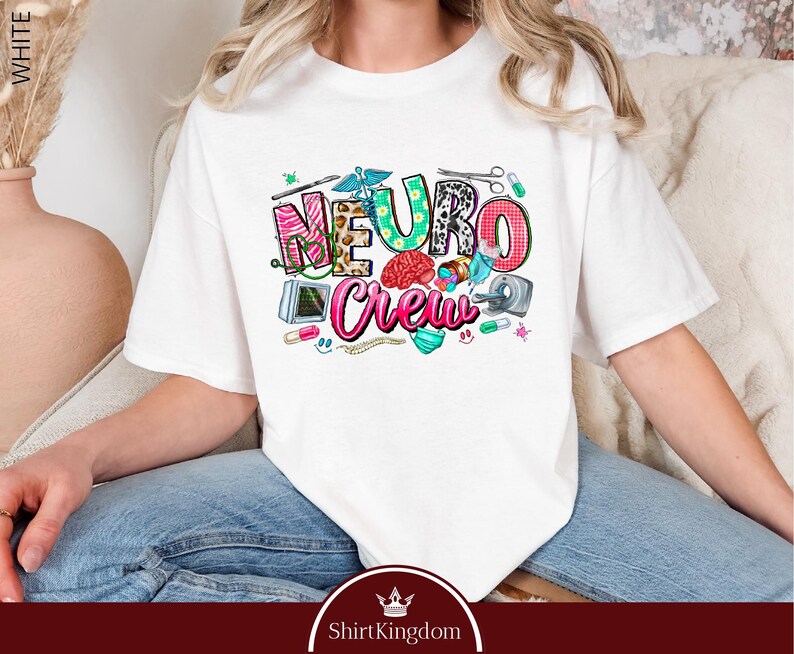 A person wearing a white t-shirt with a colorful graphic design featuring the word "Neuro Crew" and various medical and healthcare-related icons.
