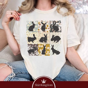 a woman sitting on a couch wearing a t - shirt with cats on it