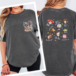 a woman wearing a gray t-shirt with various cartoon characters and text printed on it.