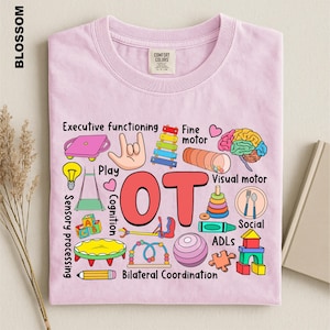May include: A light pink t-shirt featuring the large red text OT in the center, surrounded by colorful illustrations of therapy tools and brain anatomy, with labels including Executive functioning, Fine motor, Visual motor, Sensory processing, and Cognition.