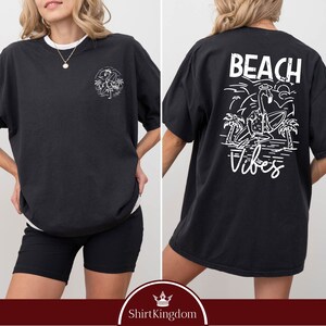 a woman wearing a black beach vibe shirt