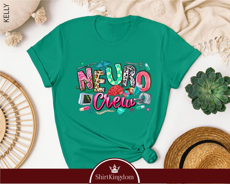 a green t-shirt with a colorful graphic design, including the word "Neuro Crew" and various medical and healthcare-related icons. The t-shirt is displayed on a white background, surrounded by other items such as a hat, a plant, and a woven basket.