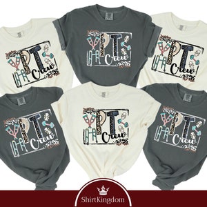 May include: Six different color t-shirts with the text "PT Crew" in a box with a graphic of crutches, dumbbells, and a physical therapy band. The shirts are in various colors, including white, gray, and black.