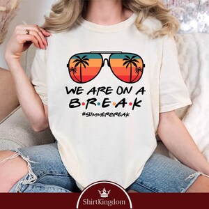 May include: Ivory t-shirt with a graphic of retro sunglasses with palm trees inside the lenses. The text "WE ARE ON A BREAK #SUMMERBREAK" is printed below the sunglasses.