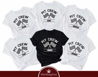 May include: A collection of five short-sleeved t-shirts, four in white and one in black, each featuring a graphic print with the text PIT CREW above two crossed checkered racing flags and a personalized name printed on a horizontal line below.