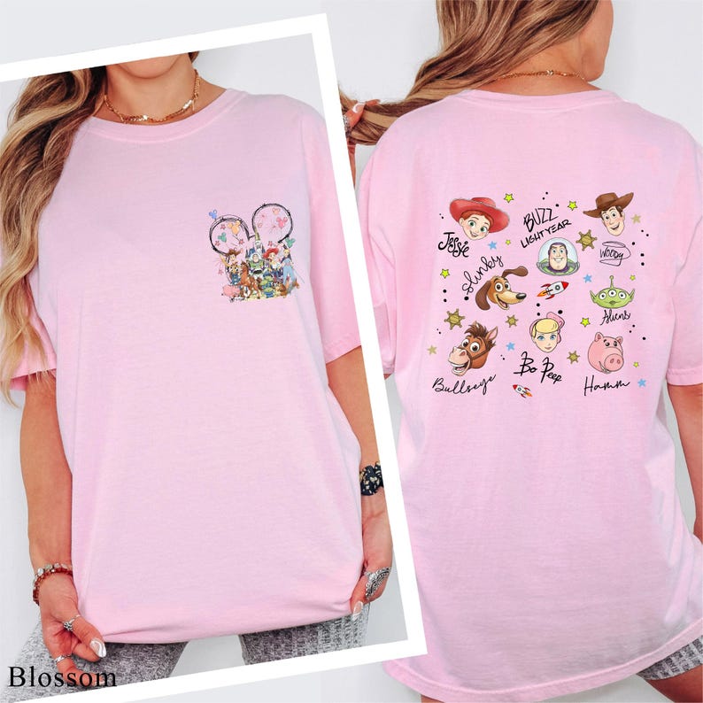 A woman wearing a pink t-shirt with various cartoon characters and text printed on it.