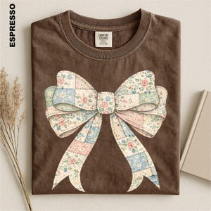 a brown t-shirt with a large floral bow design on it.