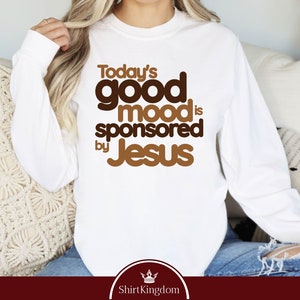 a woman sitting on a couch wearing a white shirt that says today's good