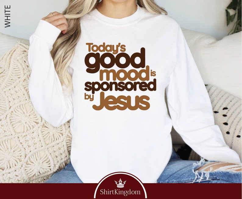 a woman sitting on a couch wearing a white shirt that says today's good