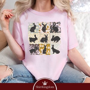 a woman sitting on a couch wearing a pink t - shirt