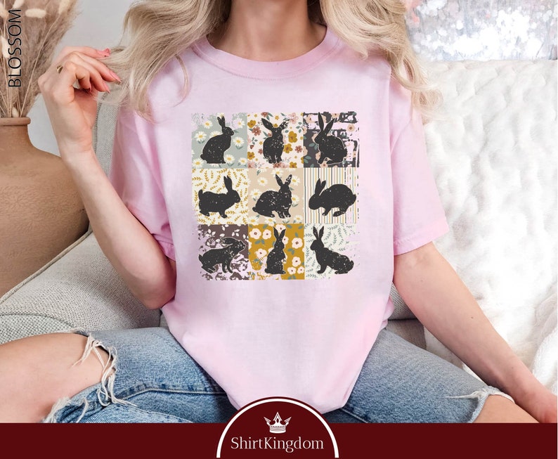 a woman sitting on a couch wearing a pink t - shirt