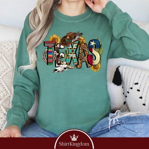 a woman sitting on a couch wearing a green sweatshirt