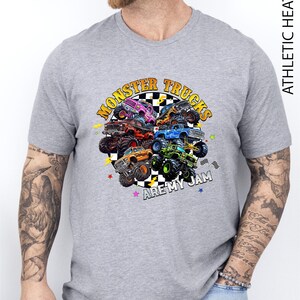 A man wearing a gray t-shirt with a graphic design of various monster trucks.