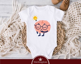 Op de afbeelding: Witte baby romper met een cartoon brein dat een bril draagt en een gloeilamp boven zijn hoofd heeft. De tekst "ShirtKingdom" staat onderaan de romper.